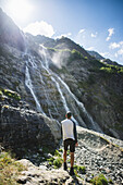 Russland, Karatschai-Tscherkessien, Arkhyz, Mann stehend in der Nähe des Sofiyskiye Vodopady Wasserfalls im Kaukasusgebirge