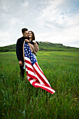 Junges Paar mit amerikanischer Flagge in einem Weizenfeld