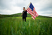 Junger Mann mit amerikanischer Flagge in einem Weizenfeld