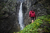Russland, Karatschai-Tscherkessien, Arkhyz, Kaukasusgebirge, Wanderer steht am Wasserfall