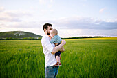 Vater mit kleinem Sohn (12-17 Monate) auf einem landwirtschaftlichen Feld