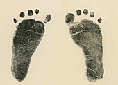 Fußabdruck mit Tinte auf Papier von beiden Füßen eines neugeborenen kleinen Mädchens
