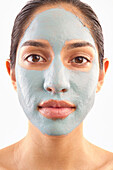 Studio-Porträt einer Frau mit blauer Gesichtsmaske