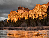 USA, Kalifornien, Yosemite National Park, Die untergehende Sonne beleuchtet den Bridalveil Fall und die Cathedral Rocks, die sich im Merced River spiegeln