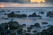 USA, Hawaii, Große Insel von Hawaii. Laupahoehoe Point Beach Park, Sonnenaufgang über Wellen und rauem Vulkangestein.