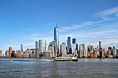 A ferry on the Hudson River passes by One World Trade Center and Manhattan buildings