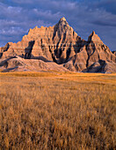 USA, South Dakota, Badlands National Park, North Unit, Frühmorgendliches Licht definiert Sturmwolken über dem Vampire Peak und herbstlich gefärbte Gräser.