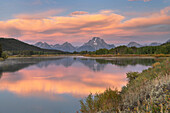 Orange clouds and Mount Moran reflected in still waters of the Snake River at Oxbow Bend at sunrise, Grand Teton National Park, Wyoming.