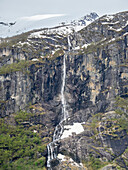 A view of a waterfall on the steep wall of mountains with the Myklebustbreen glacier at the top, Vestland, Norway, Scandinavia, Europe