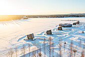 Die Holzhütten des luxuriösen Arctic Bath Spa Hotels schwimmen auf dem zugefrorenen, mit Schnee bedeckten Fluss Lule, Harads, Lappland, Schweden, Skandinavien, Europa