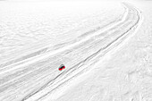 Luftaufnahme eines Autos, das auf einer leeren Eisstraße auf dem zugefrorenen Meer fährt, Lulea, Kreis Norrbotten, Lappland, Schweden, Skandinavien, Europa