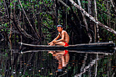 Yanomami boy sitting in a canoe on the Rio Negro River, southern Venezuela, South America