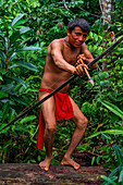 Yanomami-Mann mit Pfeil und Bogen auf einem Baumstamm, Yanomami-Stamm, Südvenezuela, Südamerika