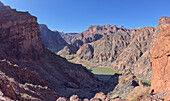 Der South Kaibab Trail schlängelt sich hinunter zur Schwarzen Brücke, die den Colorado River im Grand Canyon überspannt, mit der Phantom Ranch gleich links der Mitte, Arizona, Vereinigte Staaten von Amerika, Nordamerika
