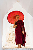 Novice monk with umbrella standing at staircase hallway at Hsinbyume pagoda, Mingun, Mandalay, Myanmar (Burma), Asia