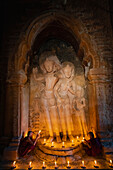 Zwei Mönchsnovizen halten Kerzen an einer Statue im Tempel, Bagan (Pagan), UNESCO-Weltkulturerbe, Myanmar (Birma), Asien