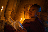 Young monk holding book inside temple, Bagan (Pagan), Myanmar (Burma), Asia