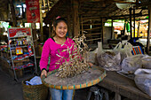 Young woman throwing dried fish in air at market, Hsipaw, Shan State, Myanmar (Burma), Asia