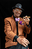 Mann sitzend, gekleidet als Dandy oder Gangster der 1950er Jahre mit Filzhut und großer Zigarre, Havanna, Kuba, Westindien, Karibik, Mittelamerika