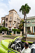 Driver in green open top Chevrolet classic car parked in suburb, Havana, Cuba, West Indies, Caribbean, Central America