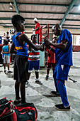 Junger Boxer wird vom Trainer mit Handschuhen angefasst, Boxing Academy Trejo, Havanna, Kuba, Westindische Inseln, Karibik, Mittelamerika