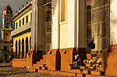 Abendliches Sonnenlicht taucht die Gebäude des Hauptplatzes und die Souvenirverkäufer auf den Stufen der Kathedrale in ein Licht, Trinidad, Kuba, Westindien, Karibik, Mittelamerika