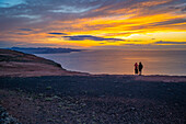 Blick auf ein Paar mit Blick auf die Vulkanküste vom Mirador del Rio bei Sonnenuntergang, Lanzarote, Las Palmas, Kanarische Inseln, Spanien, Atlantik, Europa