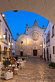 Cattedrale Santa Maria Assunta cathedral in the Largo Arcid Teodoro Trinchera square and cafe floodlit in evening, Ostuni, Brindisi province, Puglia, Italy, Europe