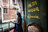Frau liest ein Buch in der Bibliothek Acqua Alta, Sestiere Castello, Venedig, Venetien, Italien