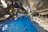 Ein Tourist bewundert den unterirdischen Fluss in der Grjótagjá-Höhle, in der Nähe des Mivathn-Sees, Norduland, Mivathn, Ostisland, Island, Europa.