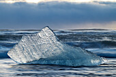 ein Eisblock am Diamond Beach während eines Sonnenuntergangs im Winter, Jokusarlon Gletscherlagune, Austurland, Island, Europa