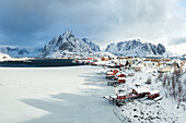 Wintertag im Dorf Reine mit schneebedecktem Berggipfel, Lofoten, Norwegen, Europa