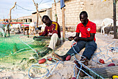 Männer reparieren Fischernetze am Strand von Saint-Louis