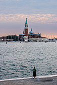 Italy, Veneto, Venice, a woman admires the Basilica of San Giorgio Maggiore at sunset