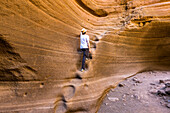 Spanien, Kanarische Inseln, Gran Canaria, Las Palmas, ein Mann erklimmt die in den Fels gehauenen Stufen der Schlucht Barranco de Las Vacas (MR)