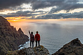 Spanien,Kanarische Inseln,Teneriffa, zwei Personen bewundern den Sonnenuntergang von den Klippen des Anaga Rural Park (MR)