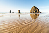 Haystack Rock und The Needles mit strukturiertem Strandsand. Cannon Beach, Clatsop County, Oregon, USA.