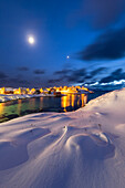 Coastal village of Sorvaer covered with snow during twilight in the cold arctic winter (Soroya Island, Hasvik, Troms og Finnmark, Norway)