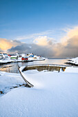 Das Küstendorf Sorvaer ist während des Sonnenaufgangs im kalten arktischen Winter mit Schnee bedeckt (Insel Soroya, Hasvik, Troms og Finnmark, Norwegen)