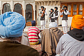 Musikanten und Geschichtenerzähler mit traditionellen Punjabi-Instrumenten und Zuschauer am Goldenen Tempel, Amritsar, Punjab, Indien