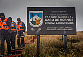 Tourists and Cape Horn National Park marker sign, Cape Horn, Tierra de Fuego, Patagonia, Chile