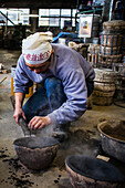 Takahiro Koizumi bereitet einen Löffel vor, um geschmolzenes Eisen in eine Form zu füllen, um eine eiserne Teekanne oder Tetsubin herzustellen, nanbu tekki, Werkstatt der Familie Koizumi, Morioka, Präfektur Iwate, Japan