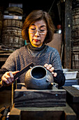 Morihisa Suzuki is putting the finishing touches at iron teapot or tetsubin, the only woman who has made teapots in the nearly 400 years of history that has molten iron crafts in Iwate, in Workshop of Morihisha Suzuki,craftsmen since 1625, nanbu tekki, Morioka, Iwate Prefecture, Japan