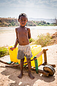 Kind arbeitet bei der Verteilung von Wasser in Containern, Morondava, Madagaskar