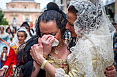 After seeing the Virgin, women in Fallera Costumes crying during Flower offering parade, tribute to `Virgen de los desamparados´, Fallas festival, Plaza de la Virgen square,Valencia