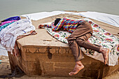 Wäscher ruht sich nach harter Arbeit aus, Dasaswamedh Ghat, im Ganges, Varanasi, Uttar Pradesh, Indien.