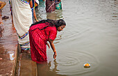 Woman making offering, in the ghats of Ganges river, Varanasi, Uttar Pradesh, India.