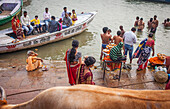 women and men praying and bathing, in the ghats of Ganges river, Varanasi, Uttar Pradesh, India.