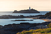 A man in front of Godrevy lighthouse at sunset, Godrevy island, Cornwall, United Kingdom, Northern Europe