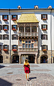 A woman observes Goldenes Dachl, Innsbruck, Innsbruck-land, Tyrol, Austria, Western Europe